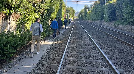 Commuters walk on Luas tracks after power outage with no indication when Green line service will resume